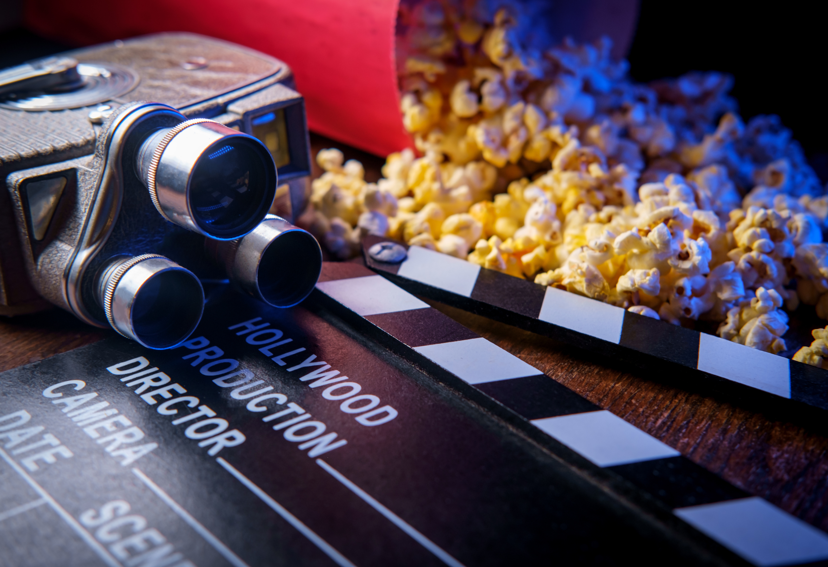 Photo of a movie projection camera on a table beside a clapperboard and spilled popcorn