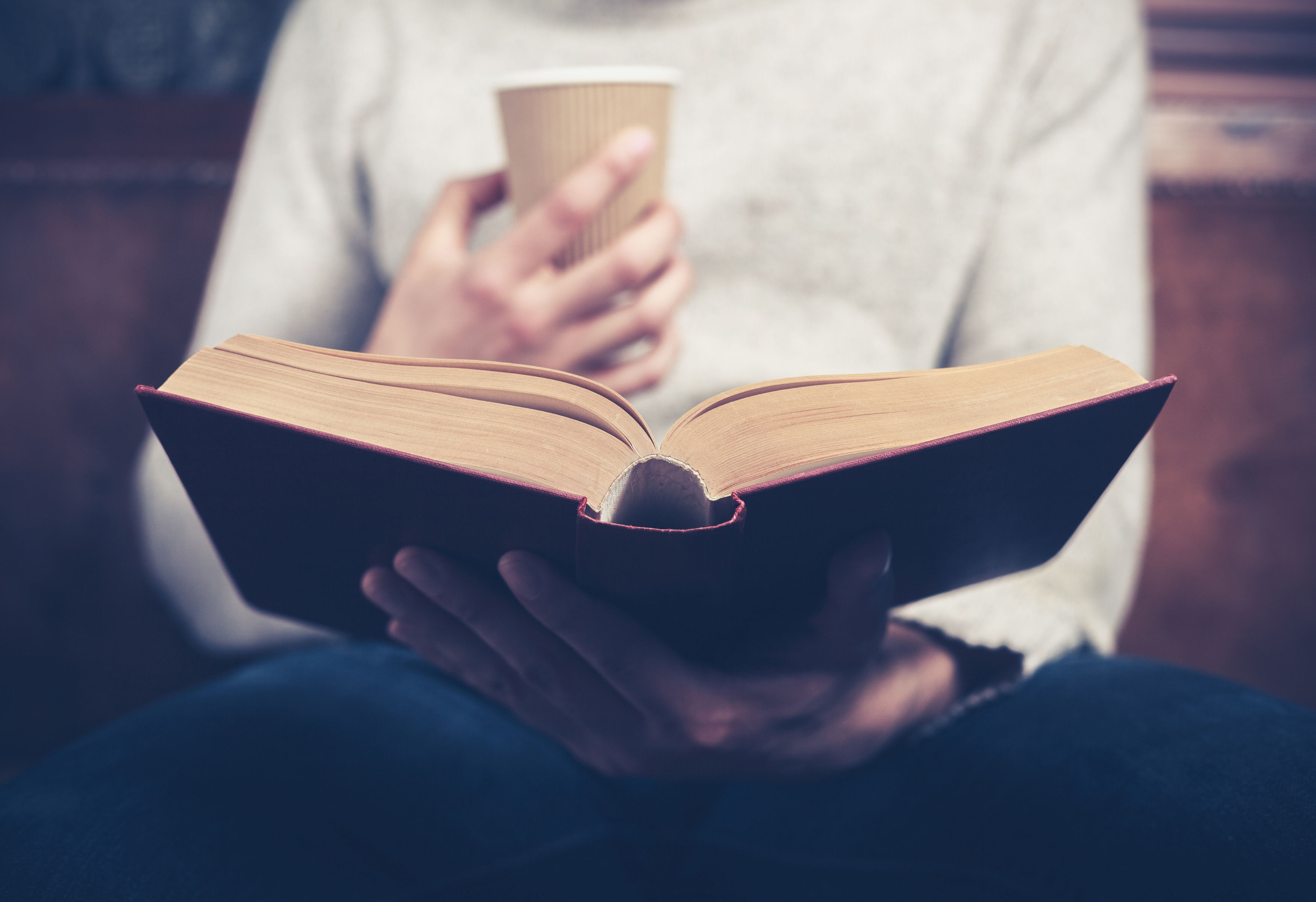 Image of a person holding a drink while reading