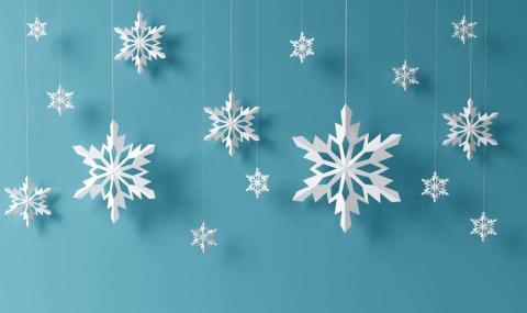 White paper snowflakes hanging in front of a blue background.